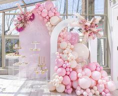 balloons and flowers decorate the entrance to a pink themed wedding reception at an indoor venue