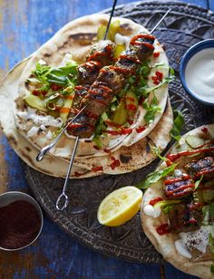 two pita breads with skewered meat and veggies on them