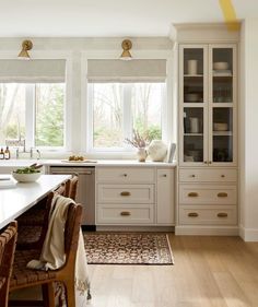 a large kitchen with white cabinets and wooden floors is pictured in this image from the dining room