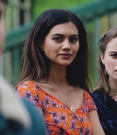 two young women standing next to each other in front of a fence and green railing