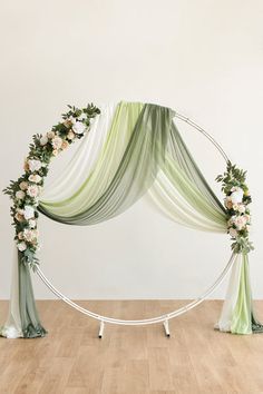 an arch decorated with flowers and greenery for a wedding ceremony or reception in the middle of a wooden floor