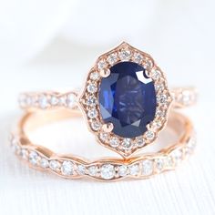 two wedding rings with an oval blue sapphire surrounded by diamonds