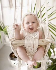 a baby sitting in a white crocheted swing