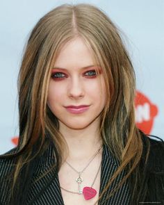 a woman with long blonde hair wearing a black jacket and red eyeshadow is looking at the camera