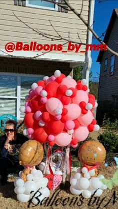 a woman sitting on the ground with balloons in front of her and a house behind her