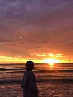 a person standing on the beach at sunset