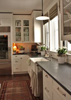 a kitchen with white cabinets and black counter tops, along with an area rug on the floor