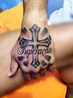 a person with a cross tattoo on their hand and the word impercado written in cursive ink