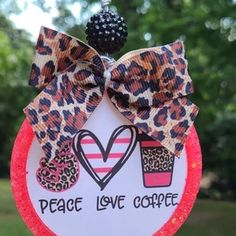 a peace love coffee ornament hanging from a tree with a leopard print bow