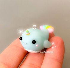 a hand holding a tiny blue toy with a unicorn horn on it's head