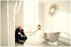 a bride and groom sitting in front of a bathtub with their feet on the floor