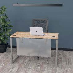 an office desk with a laptop on it in front of a blue wall and potted plant