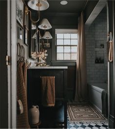 a black and white tiled bathroom with hanging lights above the sink, towels on hooks