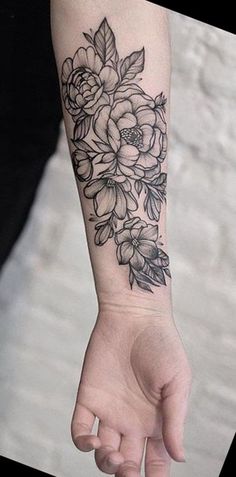 a woman's arm with flowers on it and a hand holding the wrist tattoo