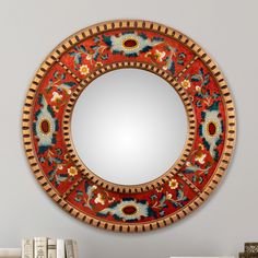 a round mirror sitting on top of a table next to a bookshelf filled with books