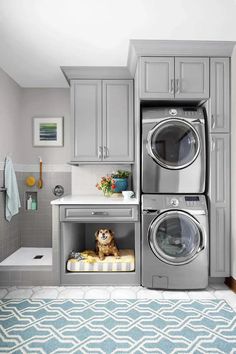 a washer and dryer in a small room with blue rug on the floor