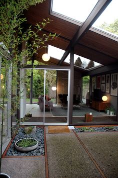 the inside of a modern house with glass walls and windows on both sides, surrounded by gravel