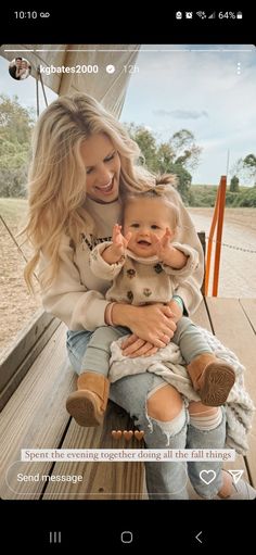 a woman holding a baby sitting on top of a wooden bench