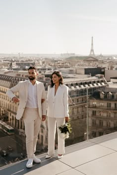 a man and woman standing on top of a building with the eiffel tower in the background