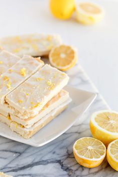 lemon shortbreads are stacked on a plate with sliced lemons next to them