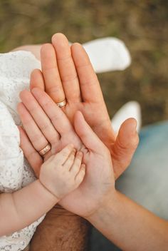 a man holding a baby's hand while wearing a wedding band on his finger