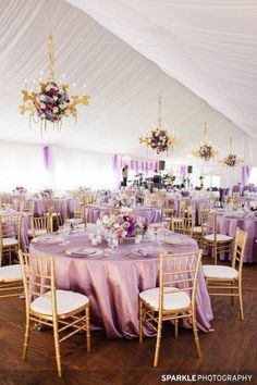 the inside of a tent with tables, chairs and chandeliers set up for an event