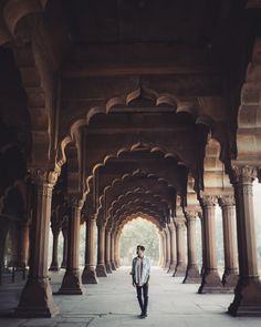 a man standing under an archway in the middle of a building with columns and arches