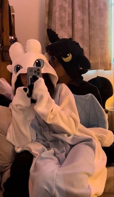 two people in animal costumes sitting on a couch with one person holding a remote control