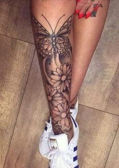 a woman's legs with flowers and butterfly tattoos on her leg, while she is wearing