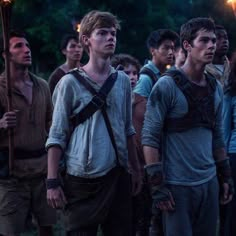 a group of young men standing next to each other in front of some trees at night