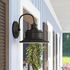 an outdoor light hanging on the side of a house with flowers in vases next to it