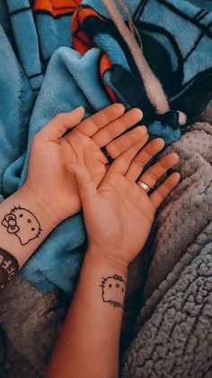 a person's hand with two small tattoos on their wrist and the other arm