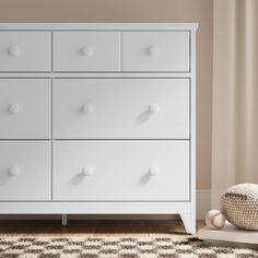 a white dresser sitting on top of a wooden floor next to a rug and window