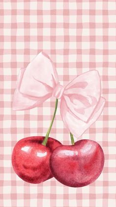 two cherries on a pink checkered tablecloth with a bow in the middle