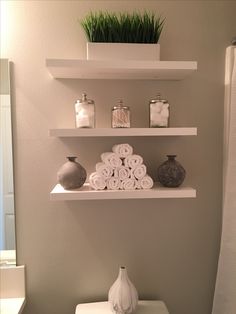 a white toilet sitting in a bathroom next to a shelf filled with towels and vases