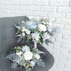 a bouquet of flowers sitting on top of a gray chair next to a brick wall