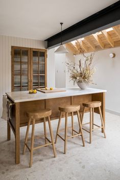 a kitchen island with stools in front of it and a vase on the counter