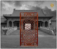 a red gate with an intricate design in front of a chinese style building on a cloudy day