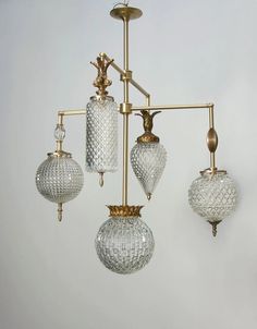 three glass lights hanging from a brass chandelier in a room with white walls