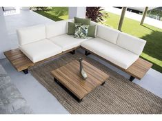 a white couch sitting on top of a wooden table next to a green planter