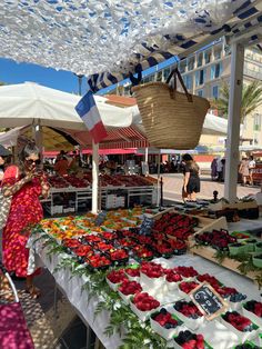 an outdoor market with flowers and fruits on display