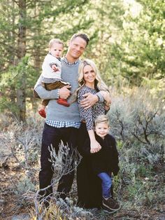 a man, woman and two children posing for a photo in the woods