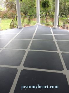 an outdoor covered patio with black and white tiles on the floor, surrounded by trees