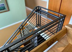 an overhead view of a stair case with metal railings and wood handrails