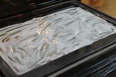 a pan filled with white frosting sitting on top of a stove