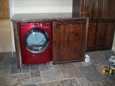 a washer and dryer sitting in a kitchen next to some wooden cupboards