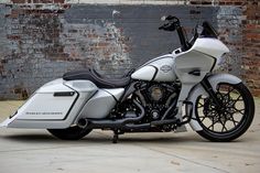 a white and black motorcycle parked in front of a brick wall