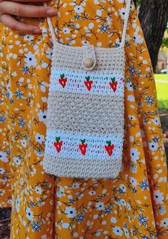 a woman is holding a crocheted strawberries purse