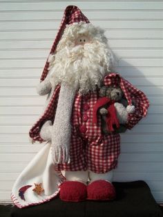 a stuffed santa clause holding a teddy bear