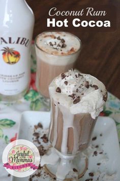 two glasses filled with hot cocoa drink on a plate next to a bottle of coconut rum